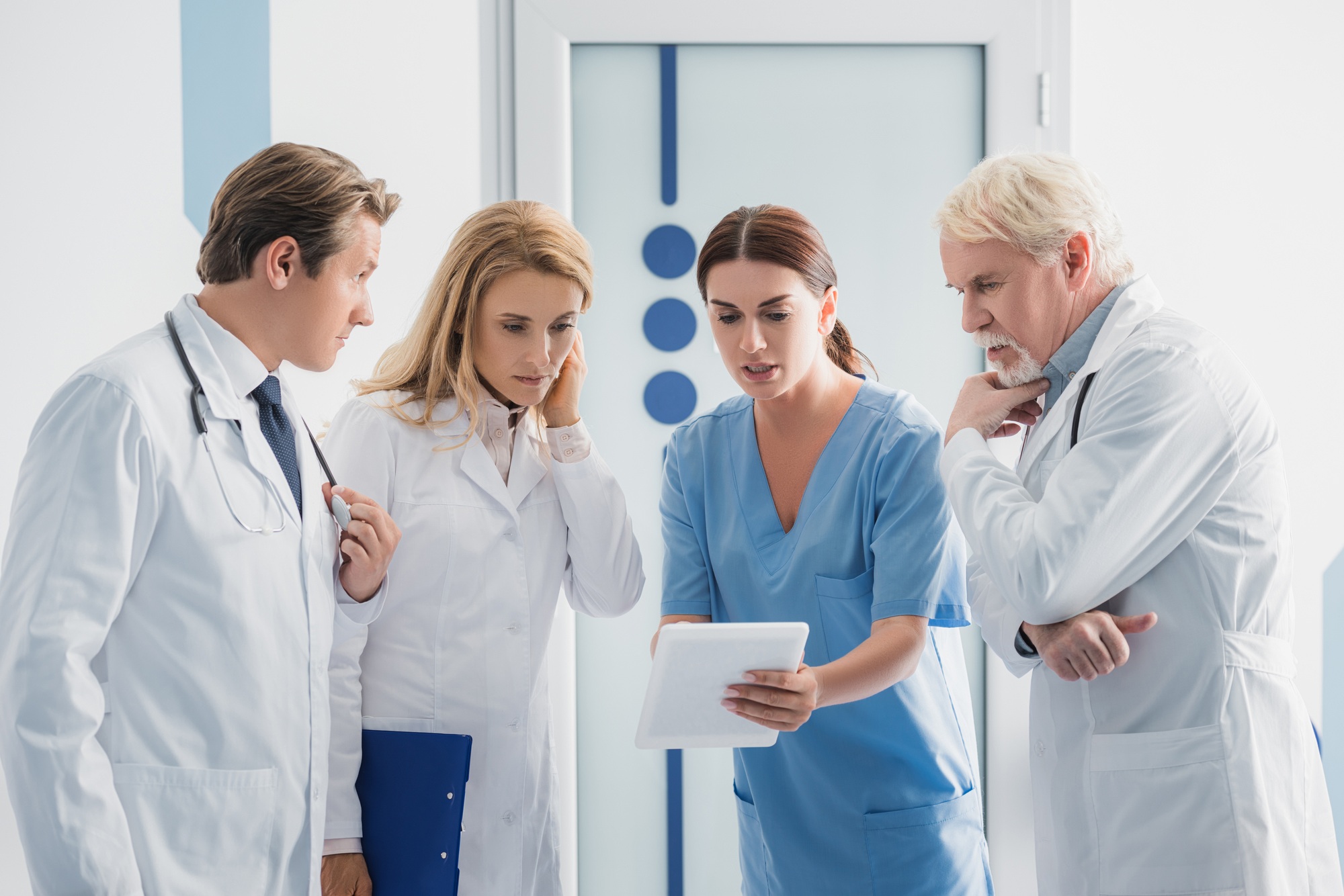 Nurse showing digital tablet to doctors in hospital