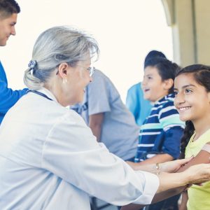 A healthcare professional administers a blood test to a young child in a clinical setting.